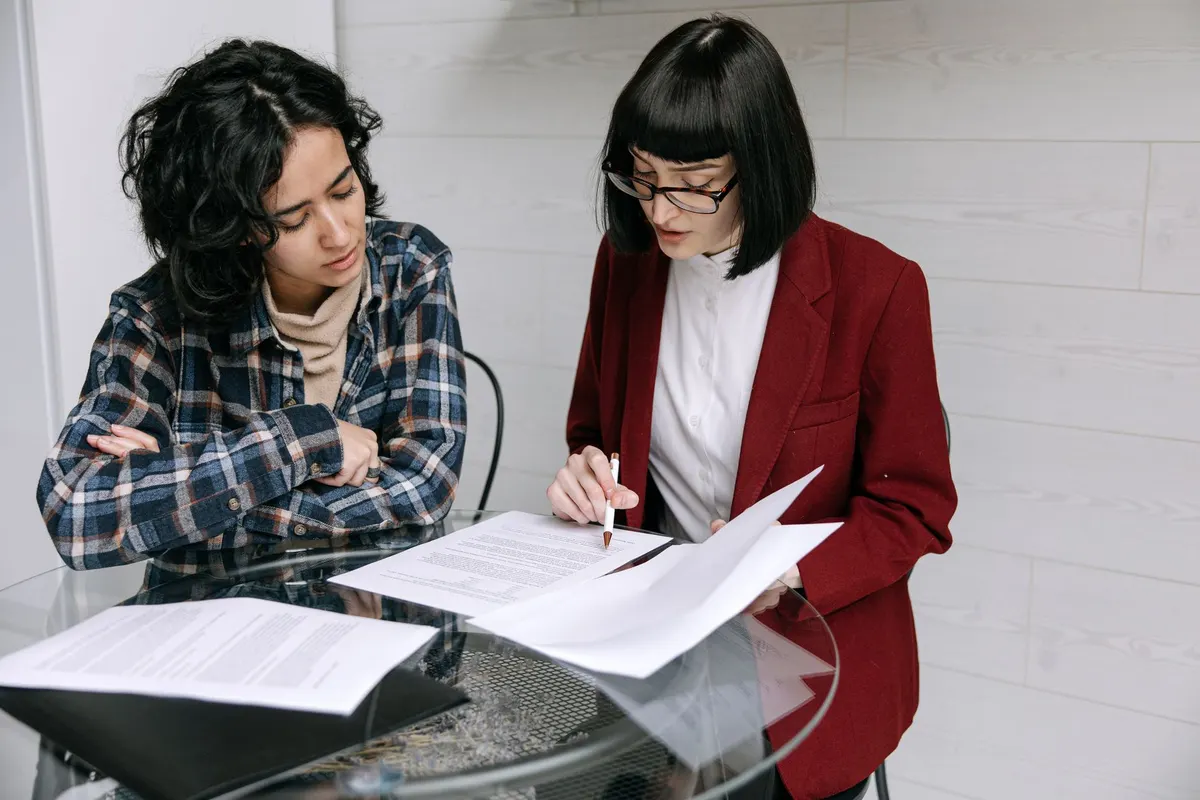 Two women at a table going through printed documents together