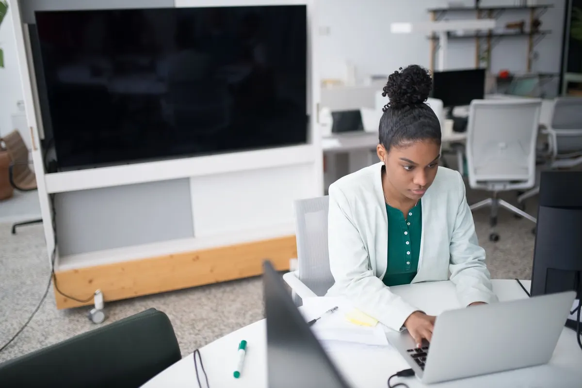 A woman working alone at a laptop at an office desk