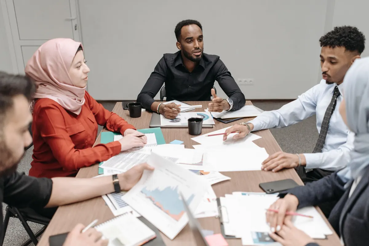 Colleagues around a table covered in printed reports and charts in a working meeting