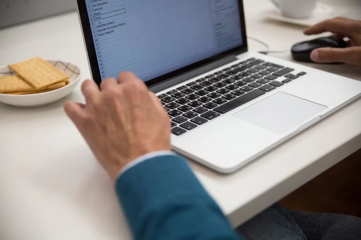 A person working on a laptop at a desk with snacks.