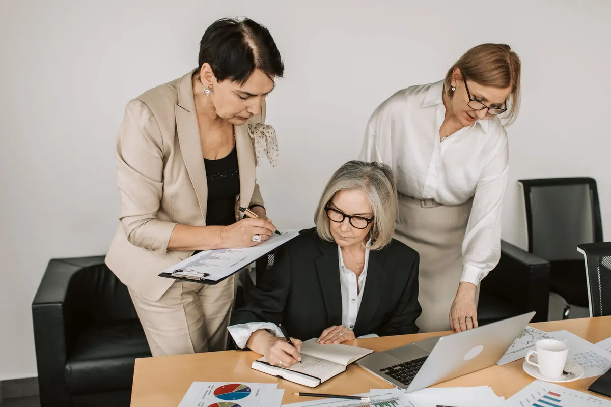 Three women reviewing a printed document together in an office